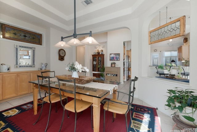 tiled dining area featuring a raised ceiling