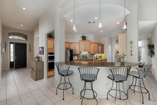 kitchen featuring a breakfast bar area, backsplash, hanging light fixtures, stainless steel appliances, and kitchen peninsula