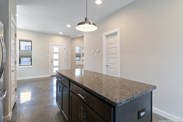 kitchen featuring pendant lighting, dark stone counters, a kitchen island, and plenty of natural light