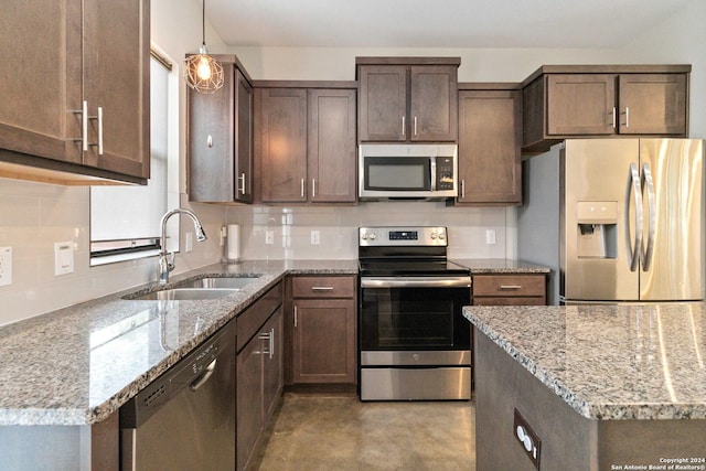 kitchen with pendant lighting, stainless steel appliances, light stone countertops, and sink