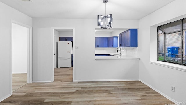 unfurnished dining area featuring an inviting chandelier, sink, and light wood-type flooring