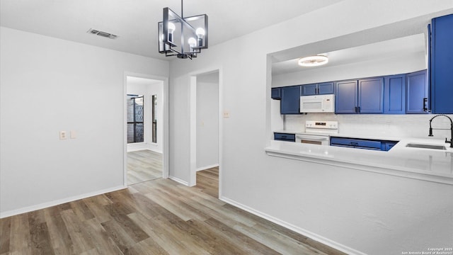 kitchen featuring blue cabinetry, sink, hanging light fixtures, white appliances, and decorative backsplash