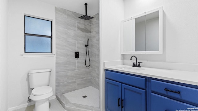 bathroom with vanity, a tile shower, and toilet