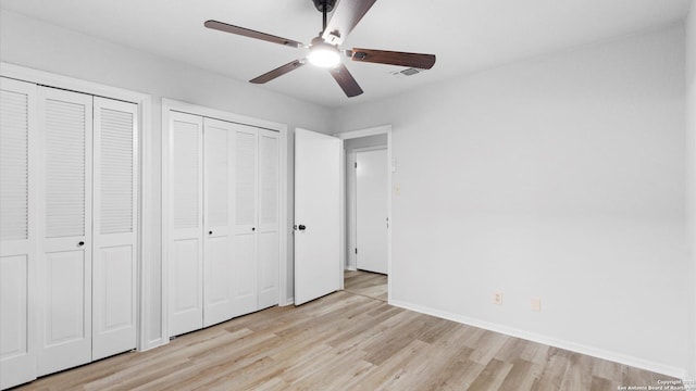 unfurnished bedroom with multiple closets, ceiling fan, and light hardwood / wood-style flooring