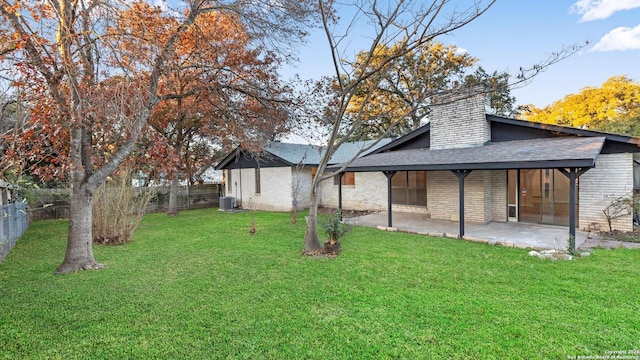 rear view of property featuring a lawn, central AC unit, and a patio area