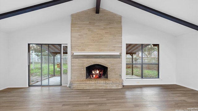 unfurnished living room featuring beamed ceiling, wood-type flooring, a fireplace, and high vaulted ceiling