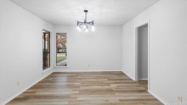 unfurnished dining area with a notable chandelier and light hardwood / wood-style floors