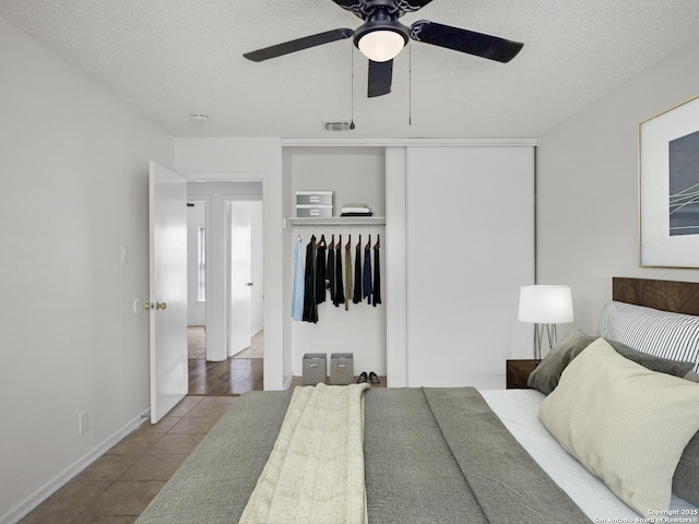 bedroom featuring light tile patterned floors, a textured ceiling, a closet, and ceiling fan