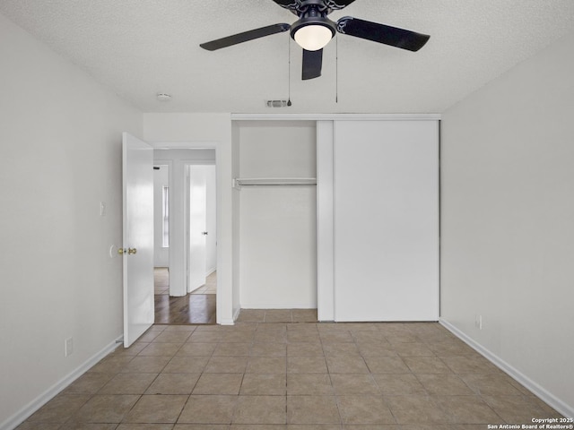 unfurnished bedroom with light tile patterned flooring, ceiling fan, a closet, and a textured ceiling