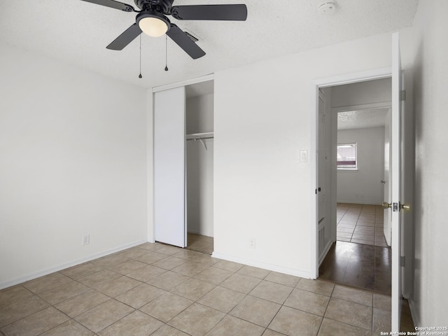 unfurnished bedroom with ceiling fan, a closet, a textured ceiling, and light tile patterned floors