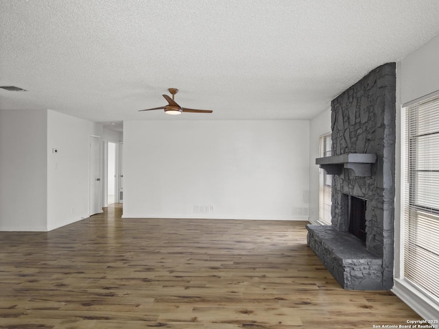 unfurnished living room with wood-type flooring, a fireplace, and a textured ceiling