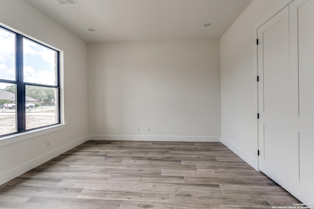 unfurnished bedroom featuring multiple windows and light hardwood / wood-style floors