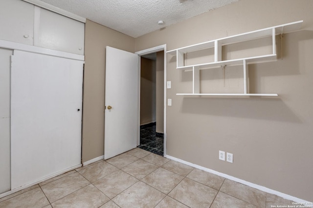 interior space with light tile patterned floors, a textured ceiling, and a closet