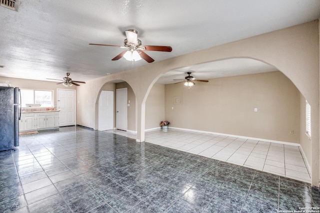 tiled empty room featuring a textured ceiling and ceiling fan