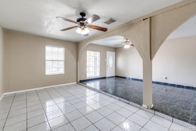 tiled empty room featuring ceiling fan and a textured ceiling