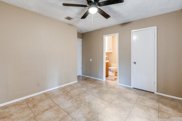 unfurnished bedroom with connected bathroom, a textured ceiling, ceiling fan, and light tile patterned floors