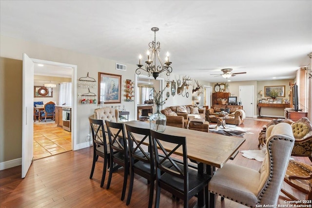 dining room featuring ceiling fan with notable chandelier and light hardwood / wood-style flooring