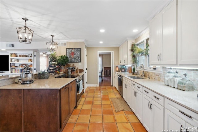 kitchen featuring sink, appliances with stainless steel finishes, hanging light fixtures, white cabinets, and light tile patterned flooring