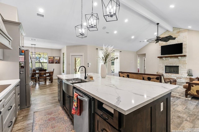 kitchen featuring appliances with stainless steel finishes, an island with sink, sink, dark brown cabinetry, and light hardwood / wood-style flooring