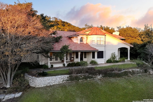 back house at dusk with a lawn