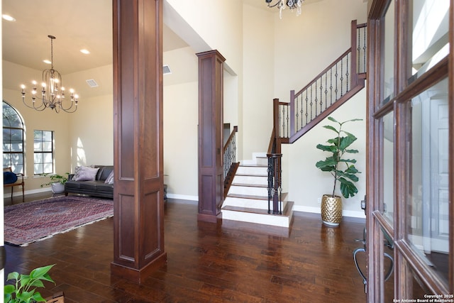 foyer featuring an inviting chandelier, dark hardwood / wood-style floors, and decorative columns