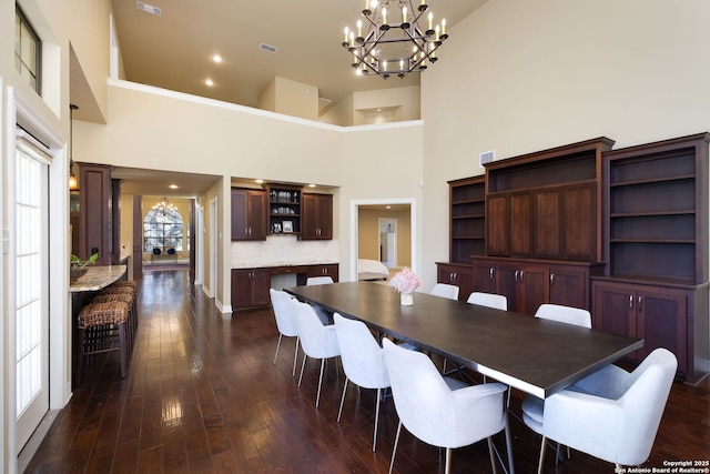 dining room featuring a towering ceiling, a chandelier, and dark hardwood / wood-style floors