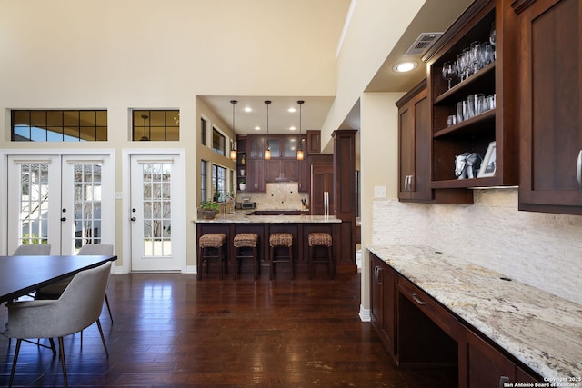 kitchen with light stone counters, decorative light fixtures, a breakfast bar, and french doors