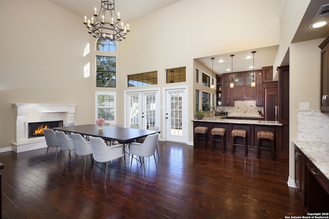 dining room with a towering ceiling, dark hardwood / wood-style floors, a fireplace, and french doors