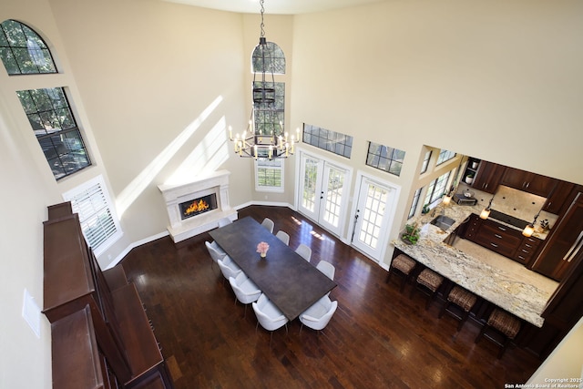 living room featuring a towering ceiling, dark wood-type flooring, and french doors