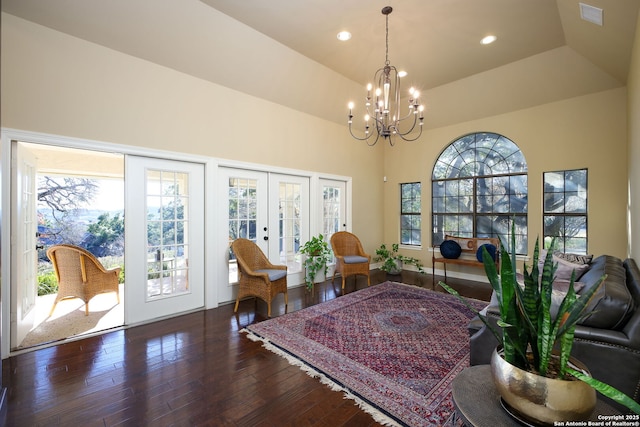 interior space featuring an inviting chandelier, dark hardwood / wood-style floors, a raised ceiling, vaulted ceiling, and french doors