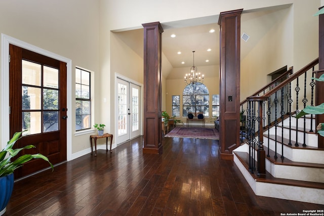 foyer with french doors, dark wood-type flooring, ornate columns, a chandelier, and a high ceiling