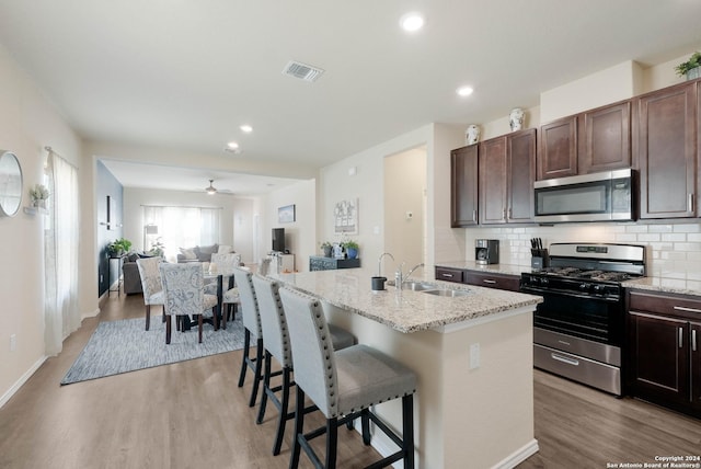 kitchen featuring appliances with stainless steel finishes, sink, a kitchen island with sink, and a kitchen breakfast bar