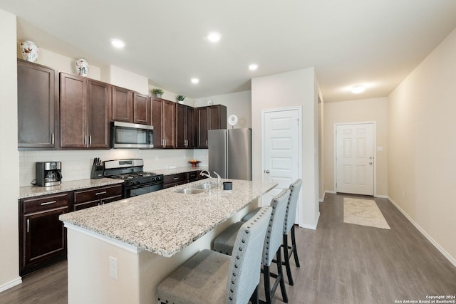 kitchen featuring tasteful backsplash, sink, a kitchen bar, stainless steel appliances, and a center island with sink