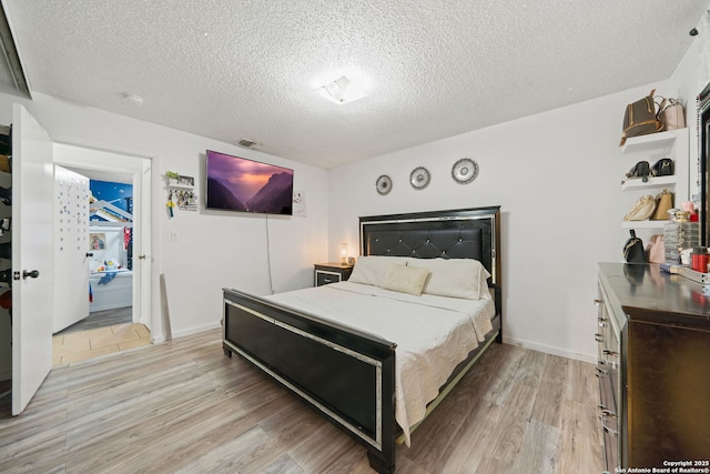 bedroom featuring a textured ceiling and light hardwood / wood-style floors