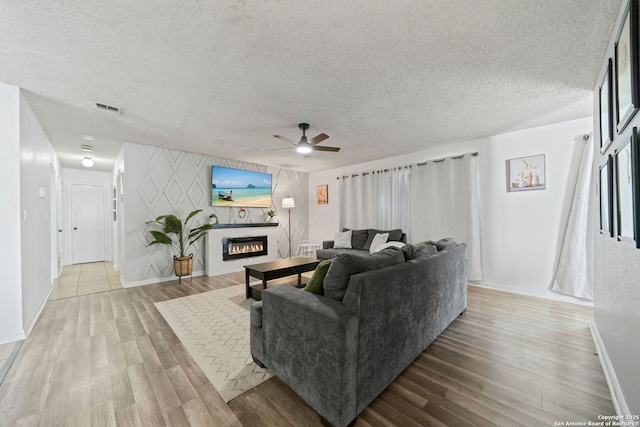 living room featuring wood-type flooring, a textured ceiling, and ceiling fan