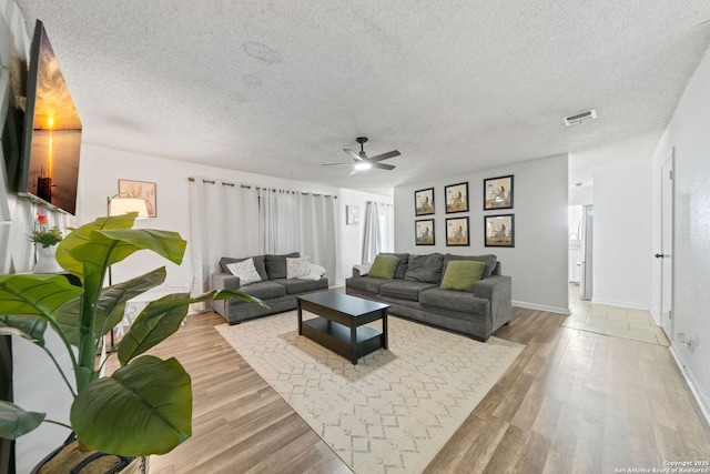 living room with ceiling fan, light hardwood / wood-style flooring, and a textured ceiling