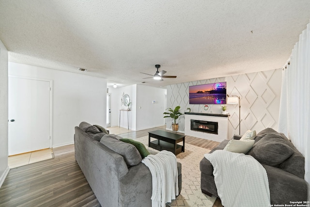 living room featuring hardwood / wood-style flooring, ceiling fan, and a textured ceiling