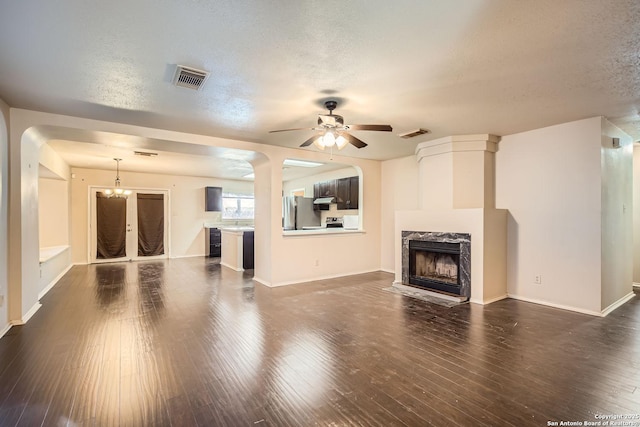 unfurnished living room with ceiling fan with notable chandelier, a fireplace, dark hardwood / wood-style floors, and a textured ceiling