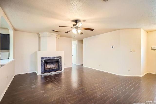 unfurnished living room featuring dark hardwood / wood-style flooring, a textured ceiling, a fireplace, and ceiling fan