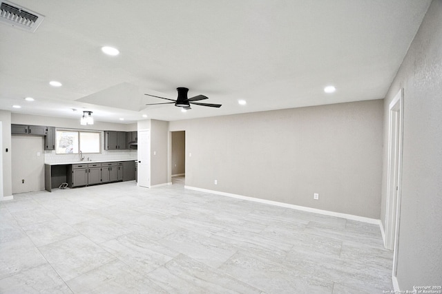 unfurnished living room with ceiling fan and sink