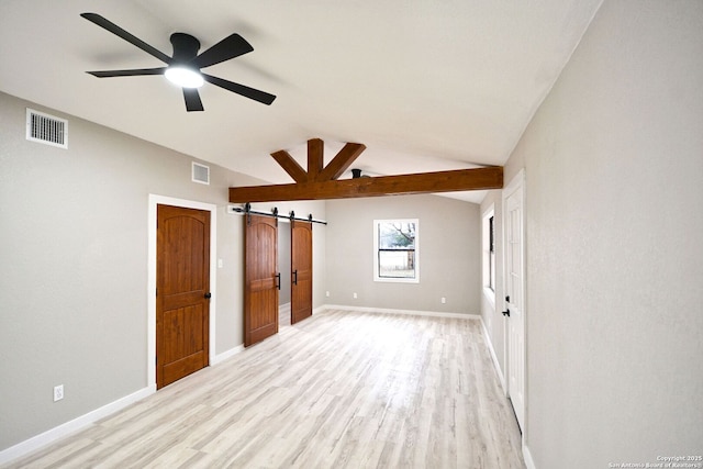 unfurnished bedroom with a barn door, lofted ceiling, ceiling fan, and light hardwood / wood-style flooring