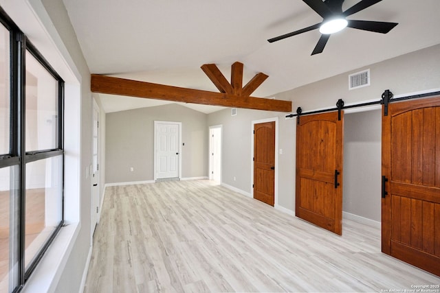 unfurnished room with a barn door, lofted ceiling, ceiling fan, and light hardwood / wood-style flooring