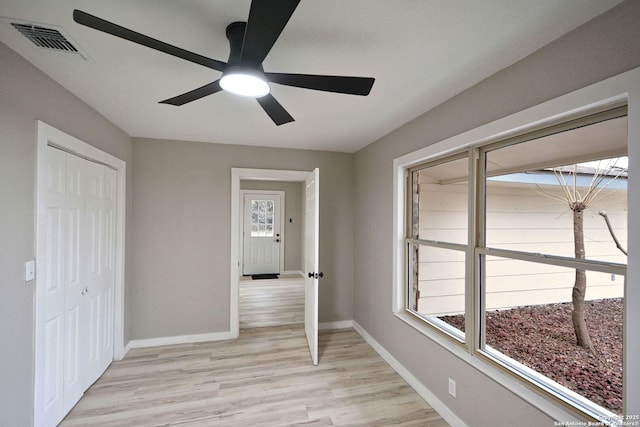 interior space with ceiling fan, a closet, multiple windows, and light wood-type flooring