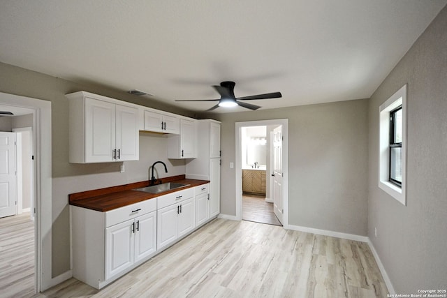 kitchen featuring light wood-type flooring, ceiling fan, sink, and white cabinets