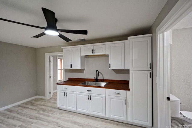 kitchen with white cabinetry, sink, wooden counters, and light wood-type flooring