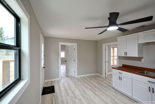 kitchen featuring wooden counters, plenty of natural light, and white cabinets