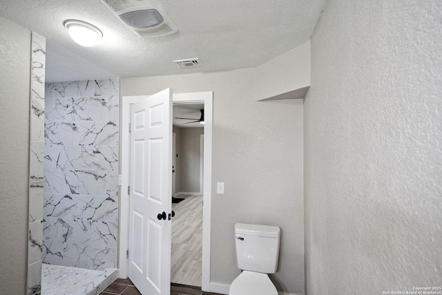 bathroom with a tile shower, hardwood / wood-style flooring, toilet, and a textured ceiling