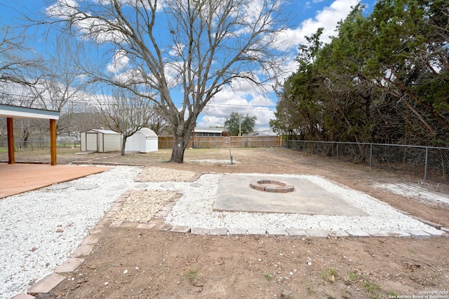 view of yard featuring a wooden deck, a fire pit, and a storage unit