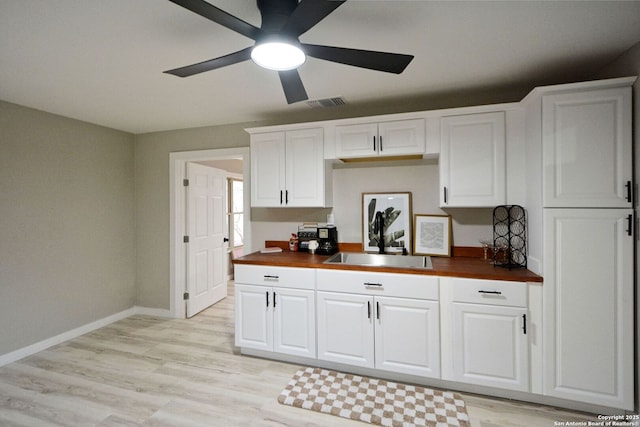 kitchen with white cabinetry, wooden counters, and light hardwood / wood-style flooring