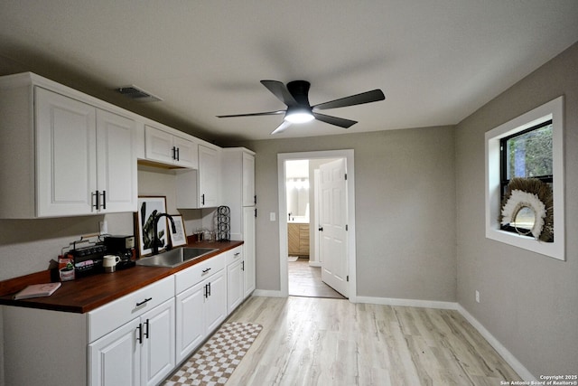 kitchen with wooden counters, sink, light hardwood / wood-style flooring, and white cabinets